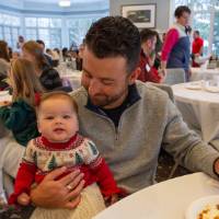 Father holds baby smiling at table during brunch